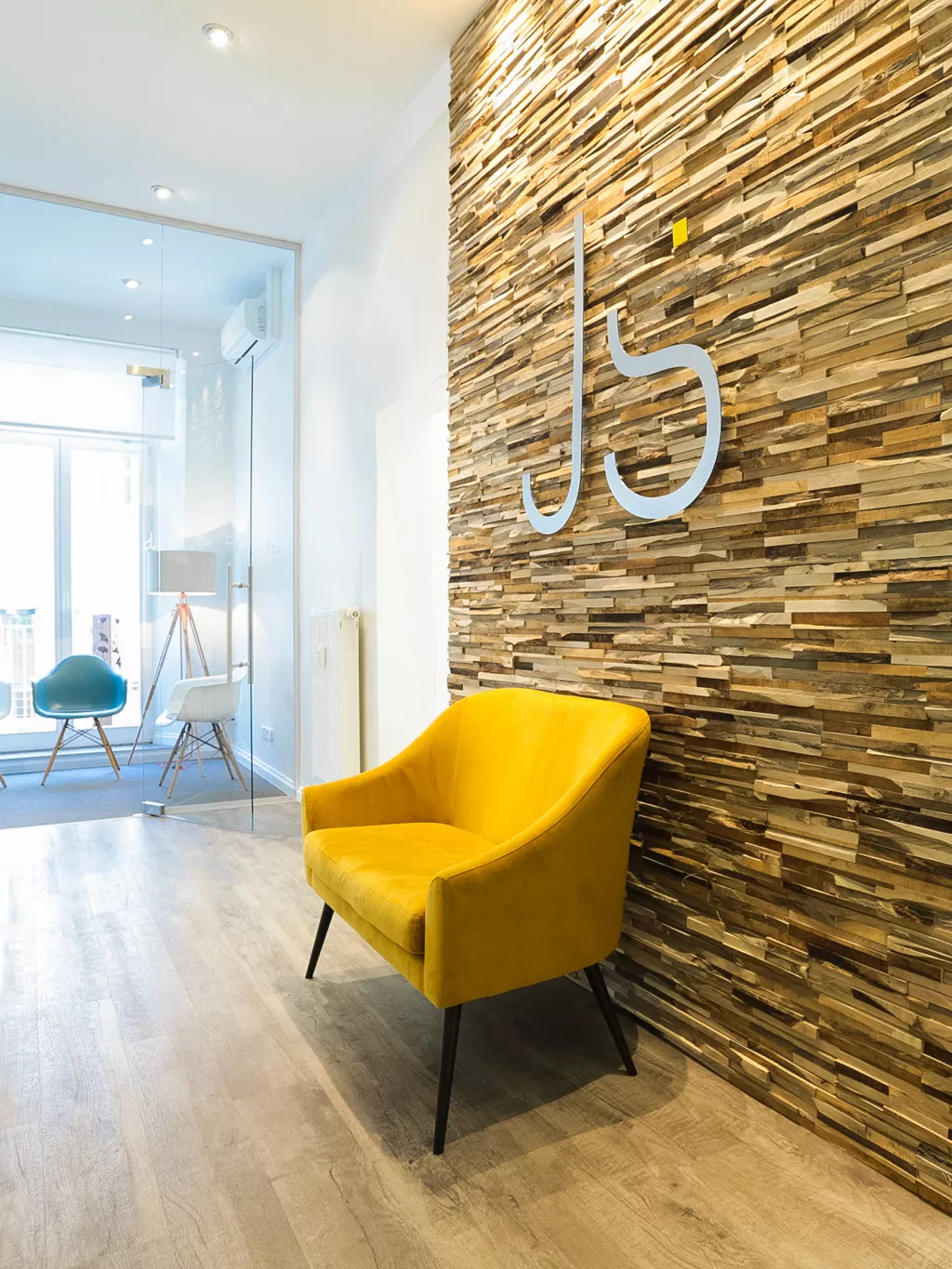 Empfangsbereich der Praxis Joy & Smile mit gelbem Sessel und Holzwand