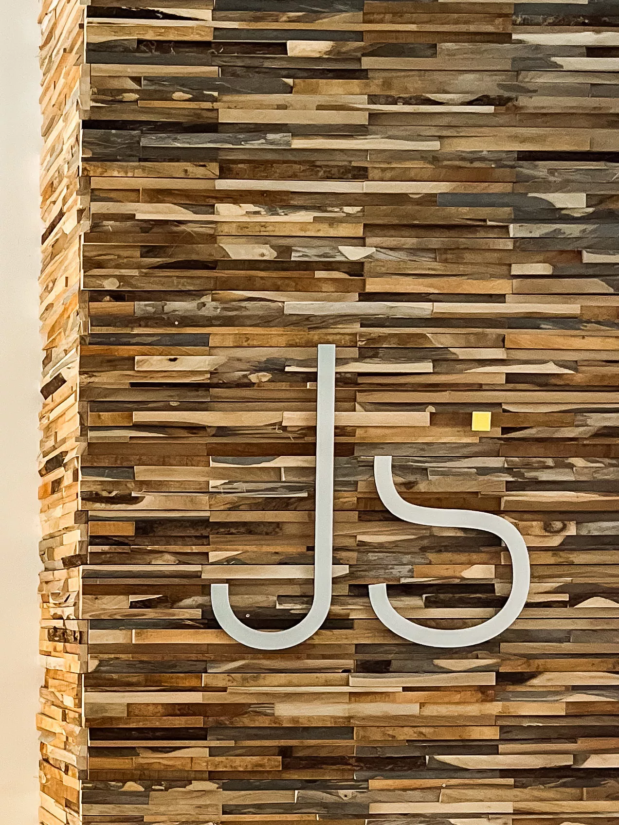 Holzwand mit J&S-Logo in der Praxis Joy & Smile