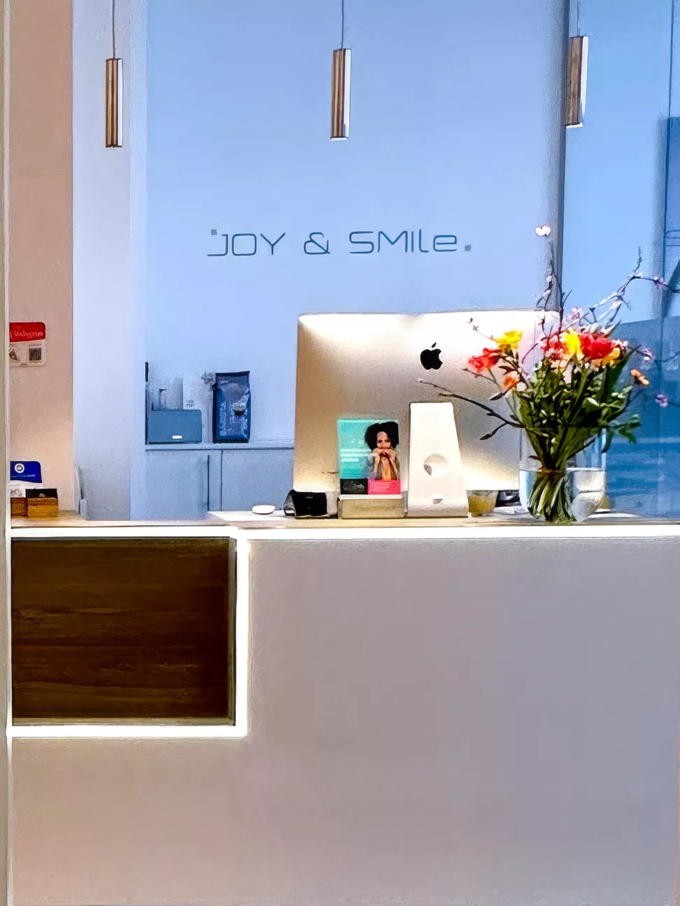 Empfangsbereich der Praxis Joy & Smile mit gelbem Sessel und Holzwand